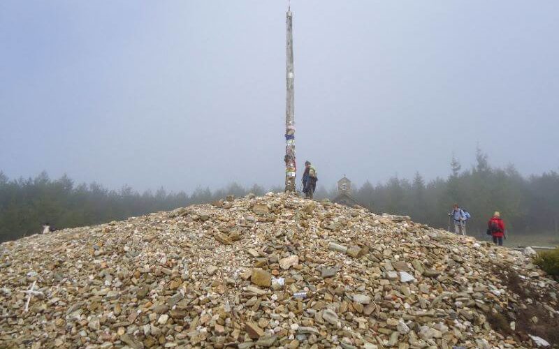 pilgrim dropping stone at cruz de fero on the Camino Frances